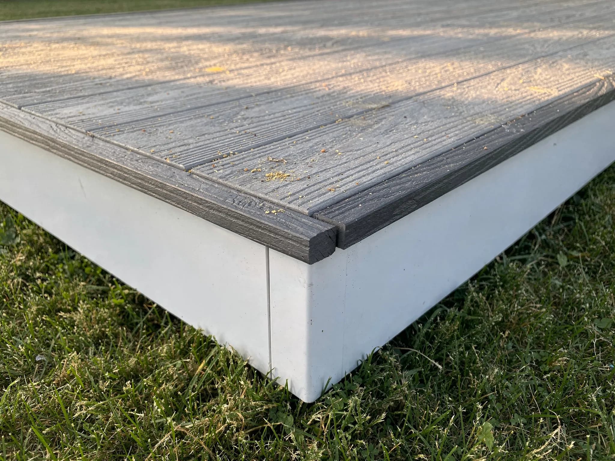 A precisely mitered picture-frame border finishes the dark slate composite decking, with hidden fasteners keeping screw heads off the walking surface.